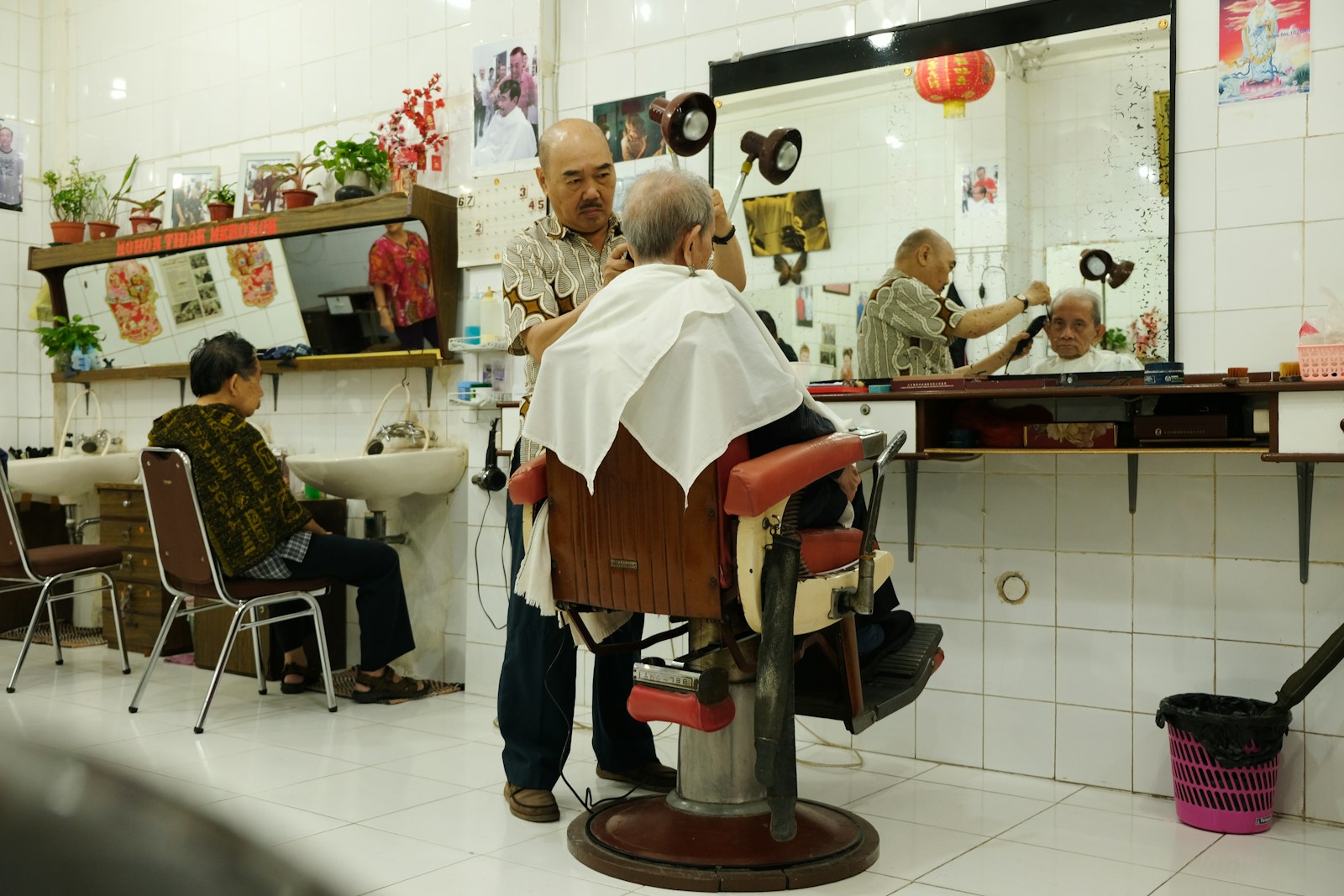 Barber lokal di Jakarta sedang memotong rambut pelanggan di kursi pangkas klasik
