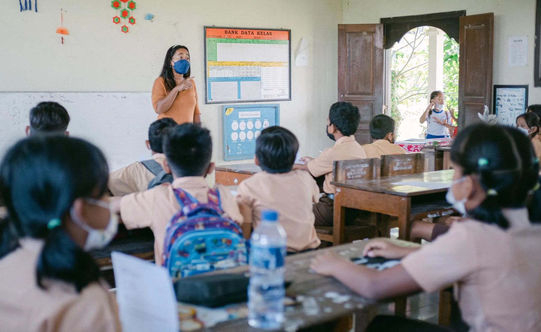 Suasana kelas di Indonesia dengan seorang pengajar dan murid-murid yang sedang mengikuti pelajaran