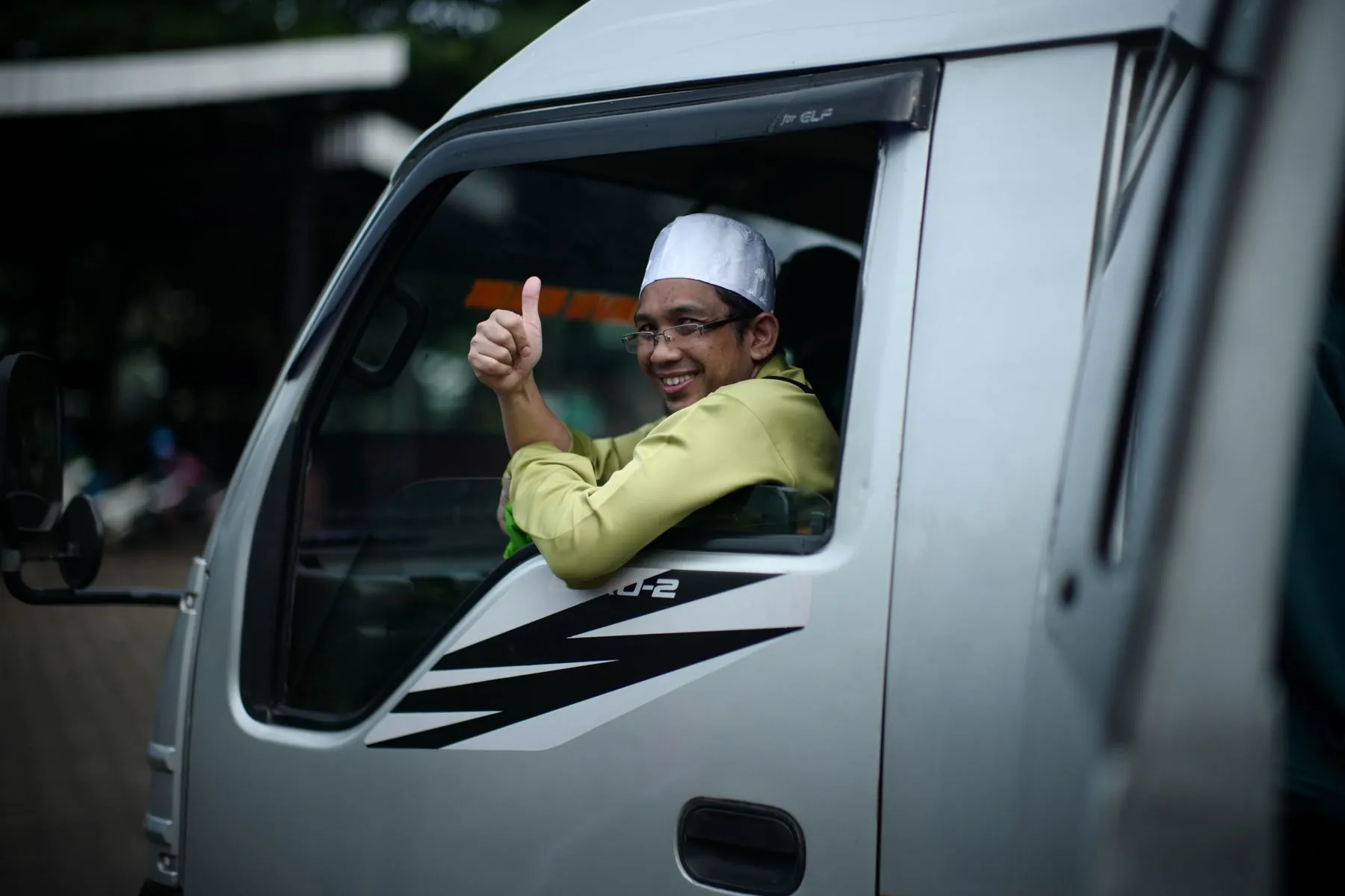 Seorang pengemudi tersenyum dari kabin van di Surabaya