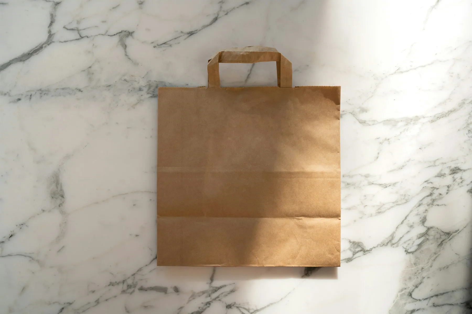Paper bag kraft polos di atas meja marmer