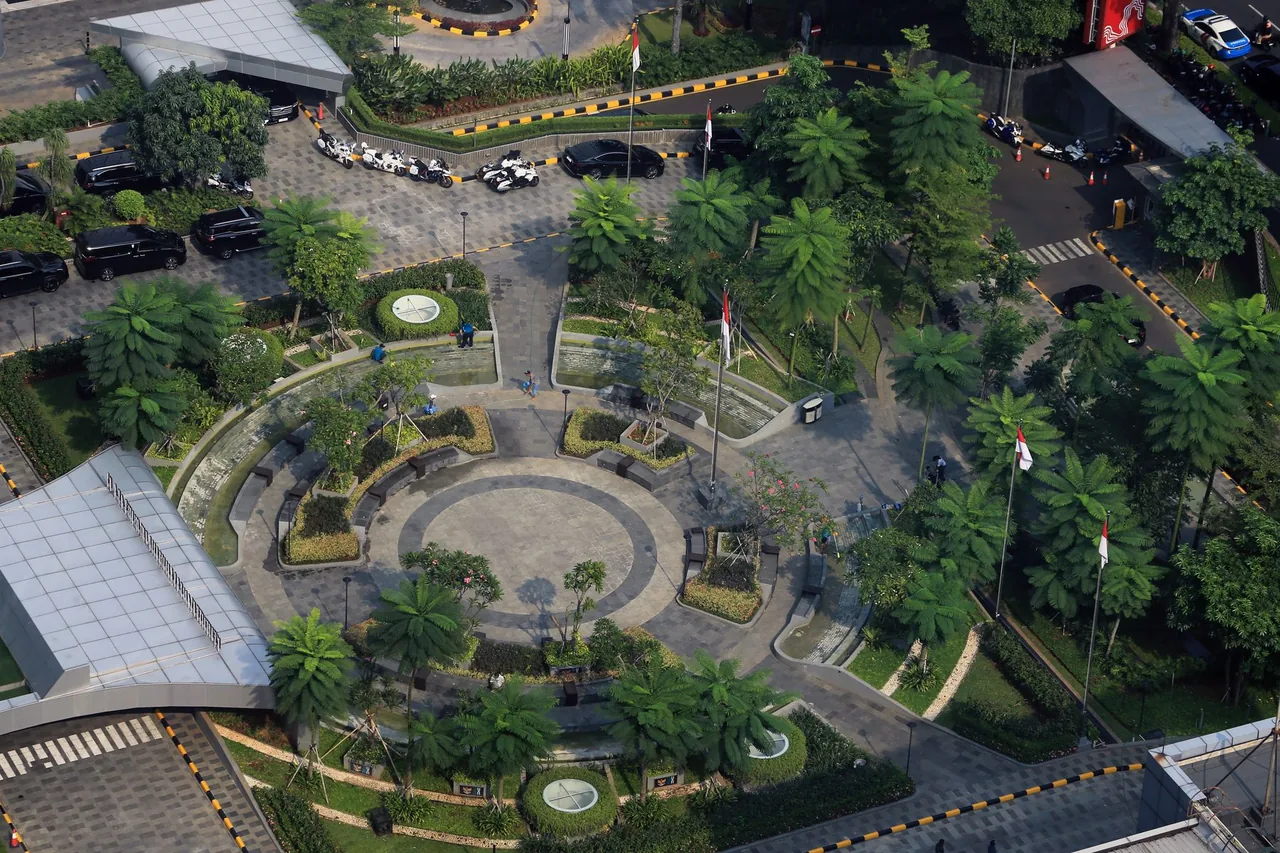 Foto udara ruang publik kota dengan taman, jalur kendaraan, dan pepohonan di Jakarta