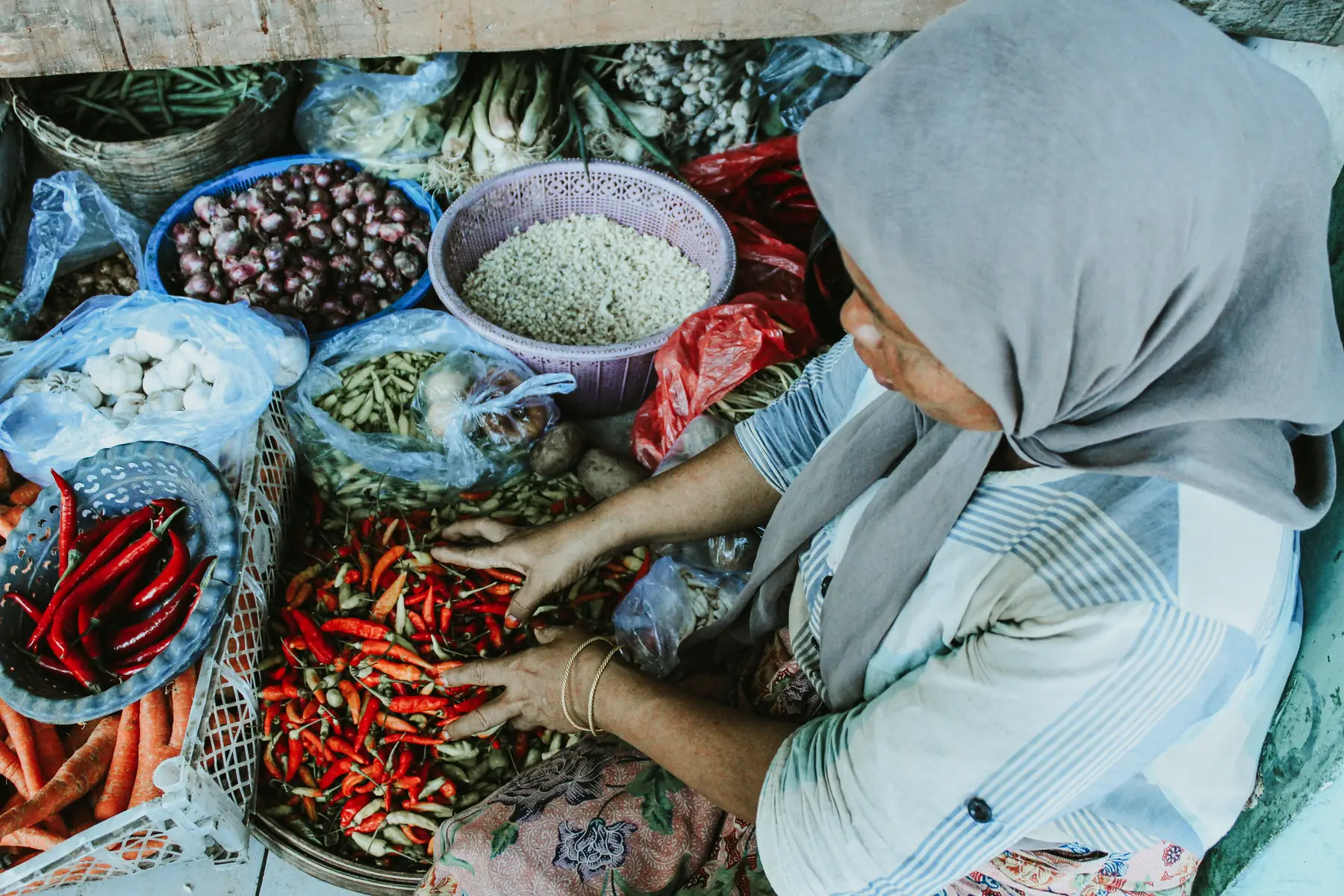 Pedagang menata cabai dan sayuran di pasar tradisional Jawa Timur, Indonesia