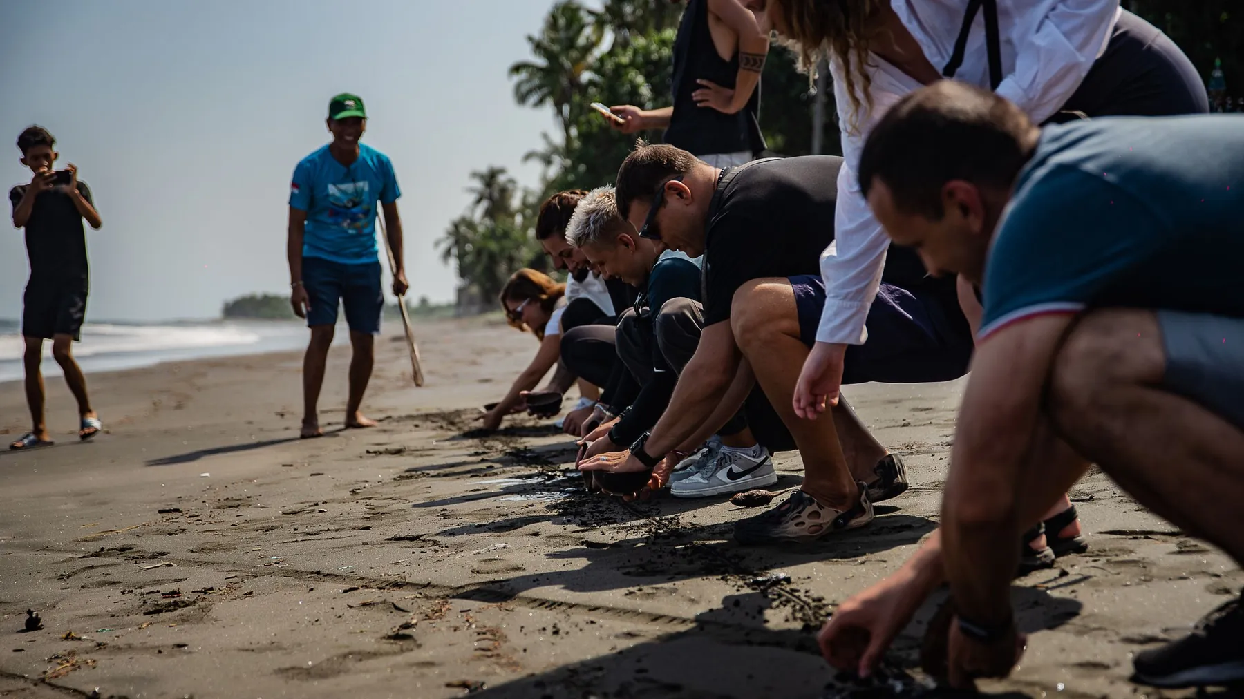 Kelompok orang mengumpulkan sampah dalam kegiatan bersih pantai di Bali