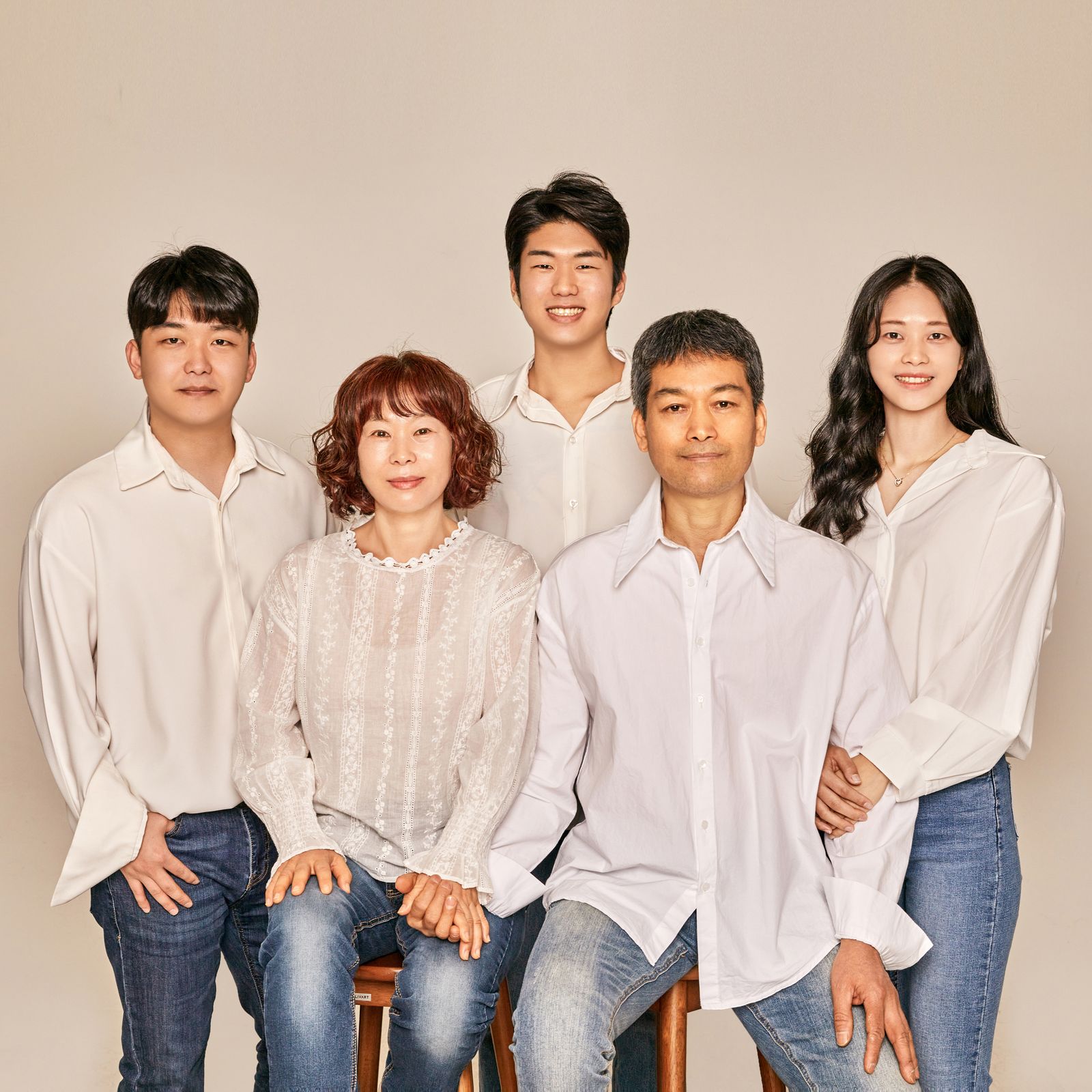Potret keluarga Asia tersenyum di studio foto dengan pakaian putih dan denim