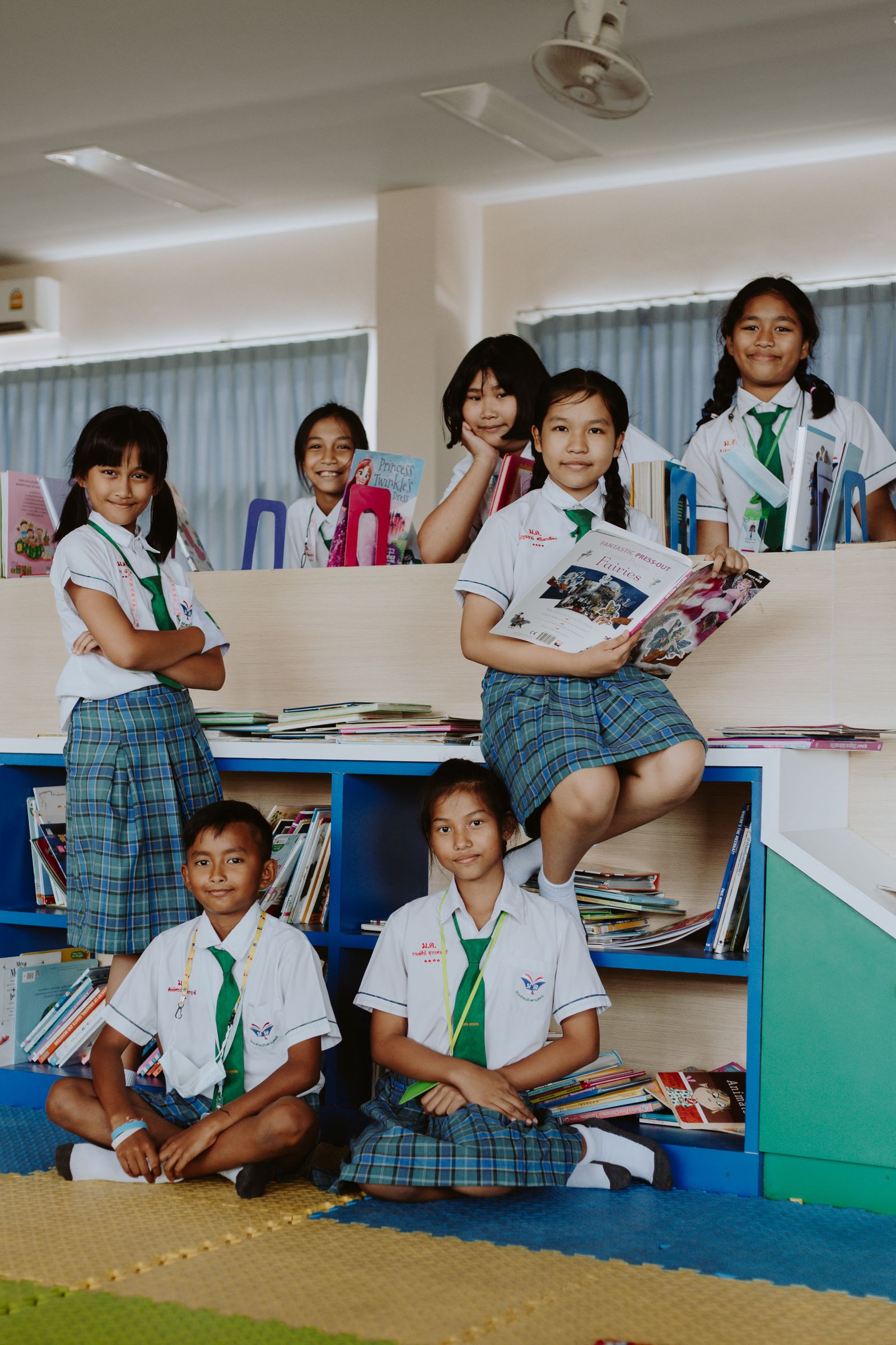 Anak-anak berdiri bersama koleksi buku di perpustakaan